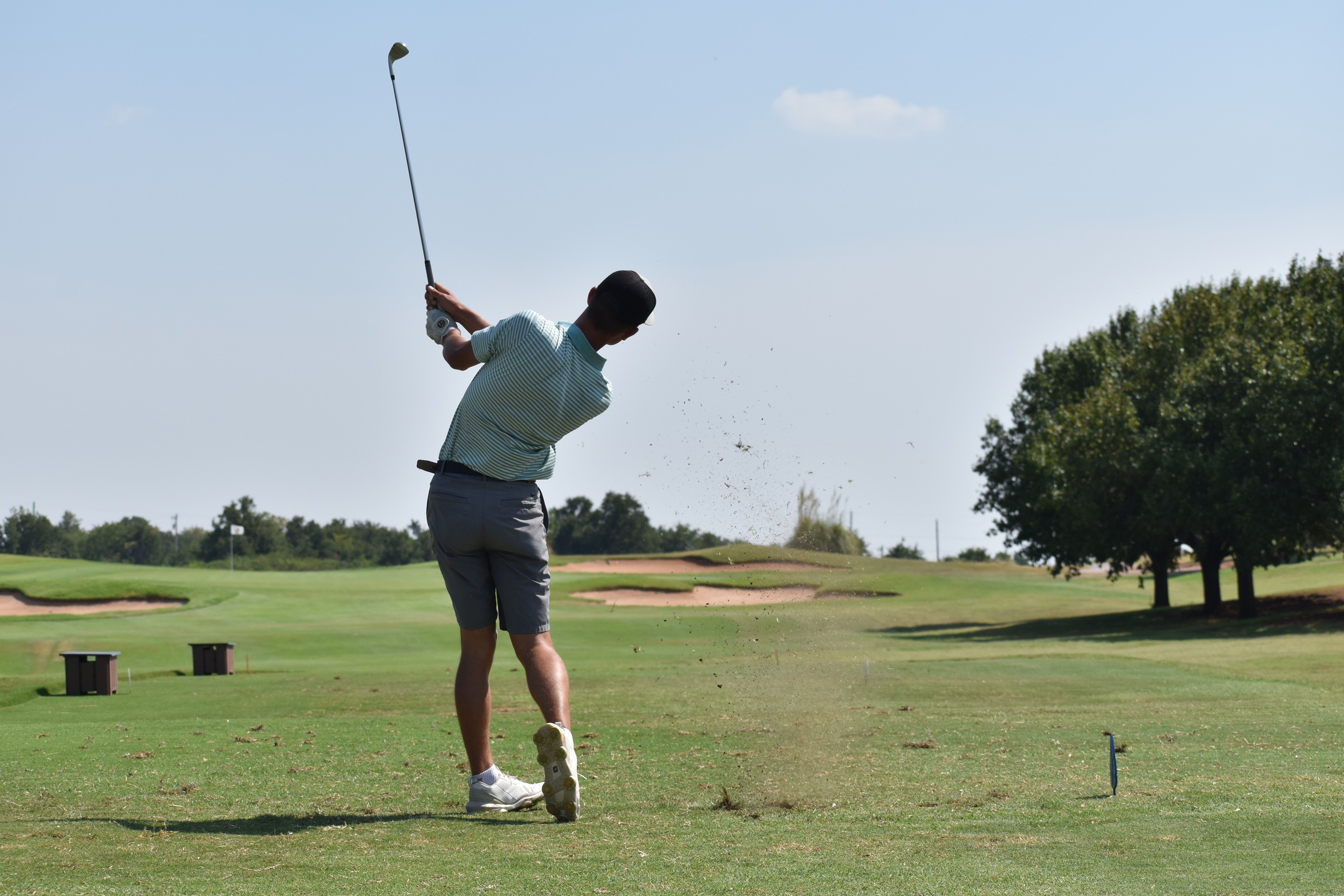 caleb smith fires a tee shot towards the green